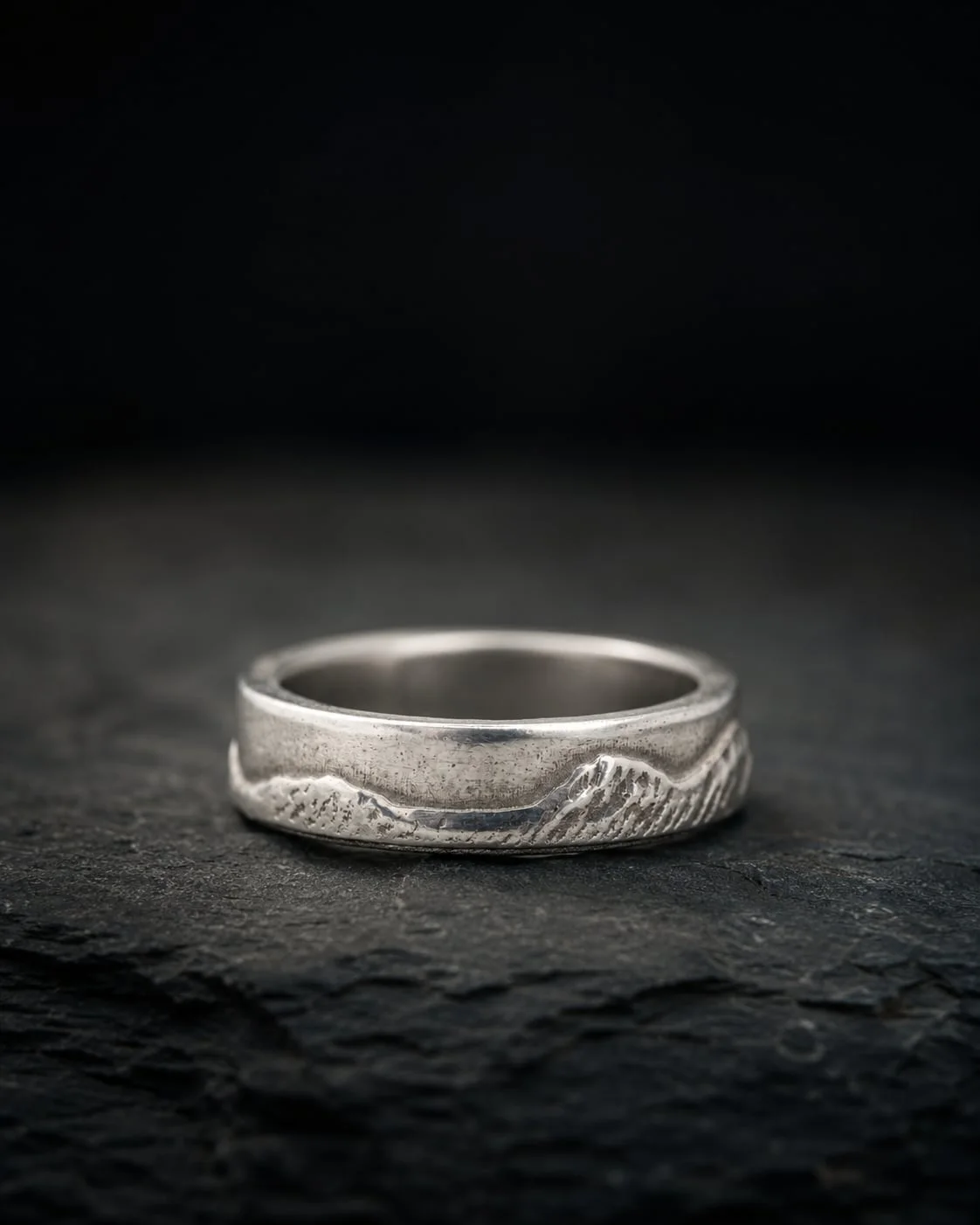 National Three Peaks sterling silver ring on dark stone.